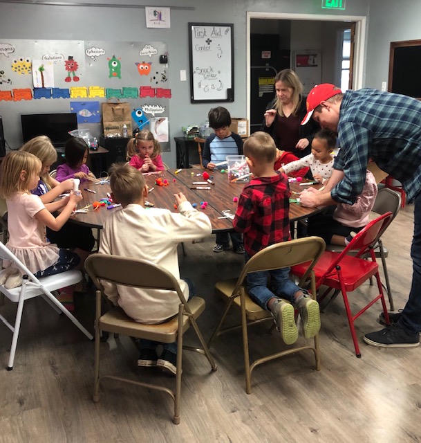 A group of young children sit at a round table and engage in a craft activity. It is the Village's Kid Vespers class.